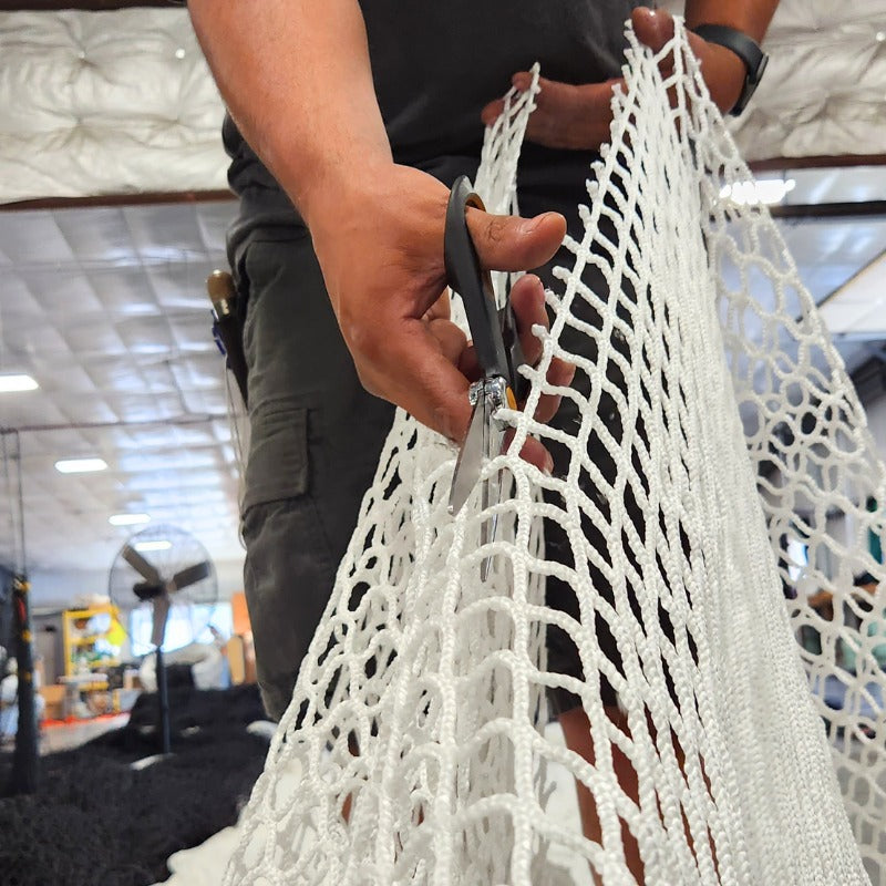 Custom netting technician cuts netting to size with scissors.
