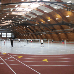 People playing games in large field house with light shining through ceiling.