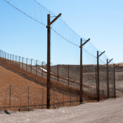 Debris & landfill netting hung by large poles along a desert road.